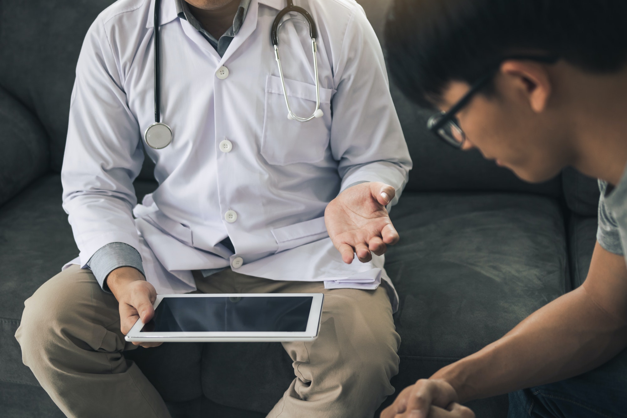 Asian doctor visited the patient at home while using the tablet explaining the patient