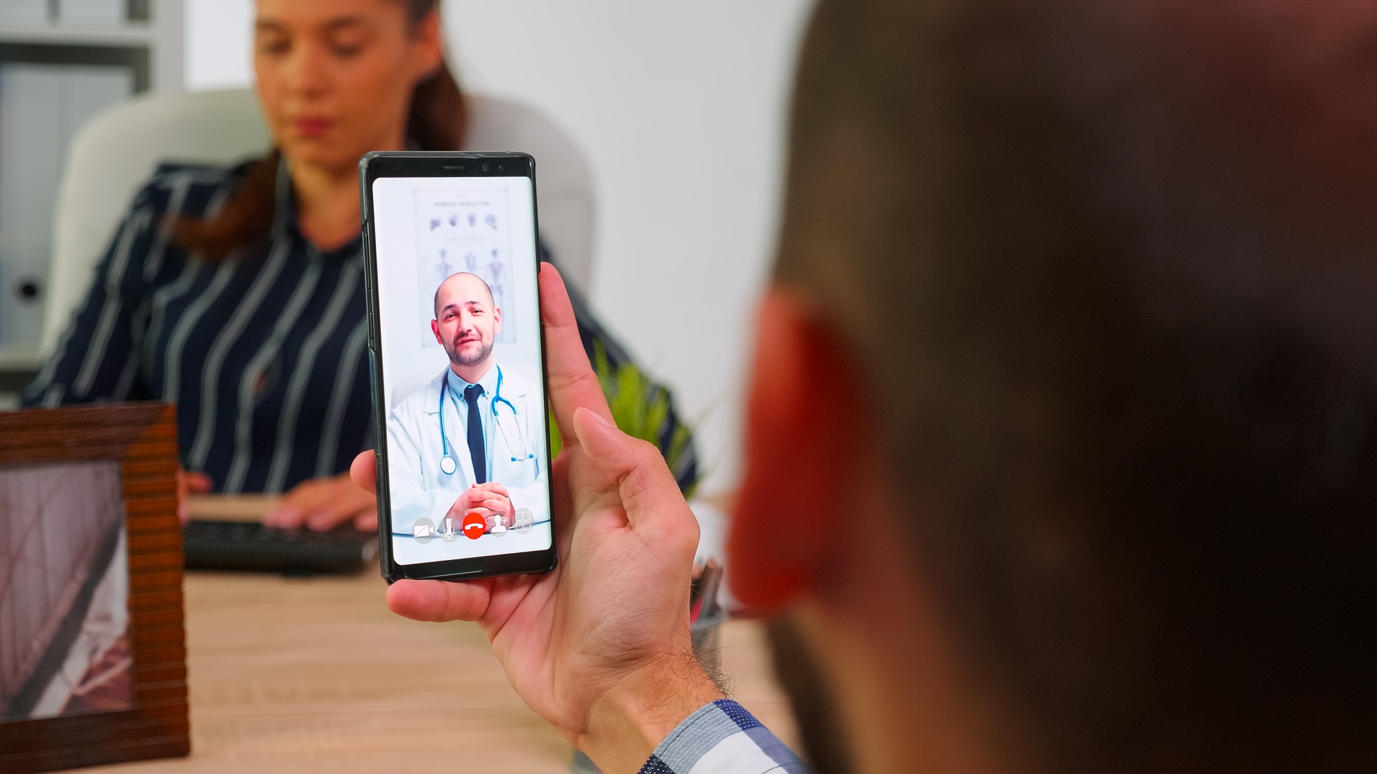 Businessman talking on video call with doctor in work time